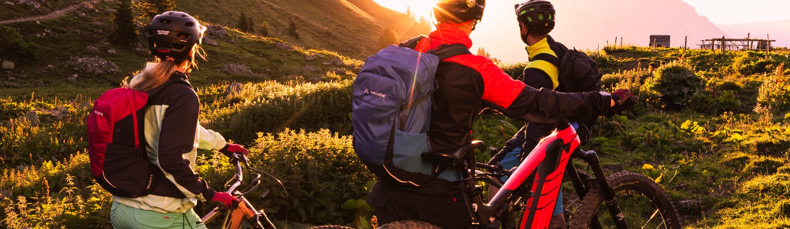 three friends are riding an e-bike withle sunset 