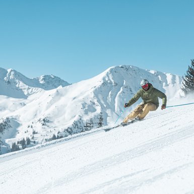 Skiier wears a green Skisuit | © Bergbahnen Fieberbrunn